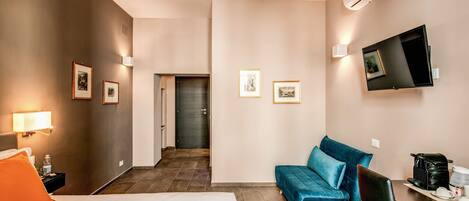 A hotel room with a bed, a desk with a coffee maker, a TV, and framed pictures on the walls.