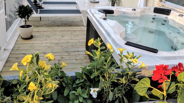 A hot tub on a wooden deck with potted plants and a view of the landscape. - Al Sfat HaBanias (HaGalil HaElyon)