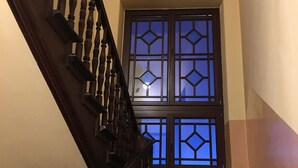 A staircase with wooden balusters and a window with a geometric pattern. - Ametyst Hostel (Kraków)