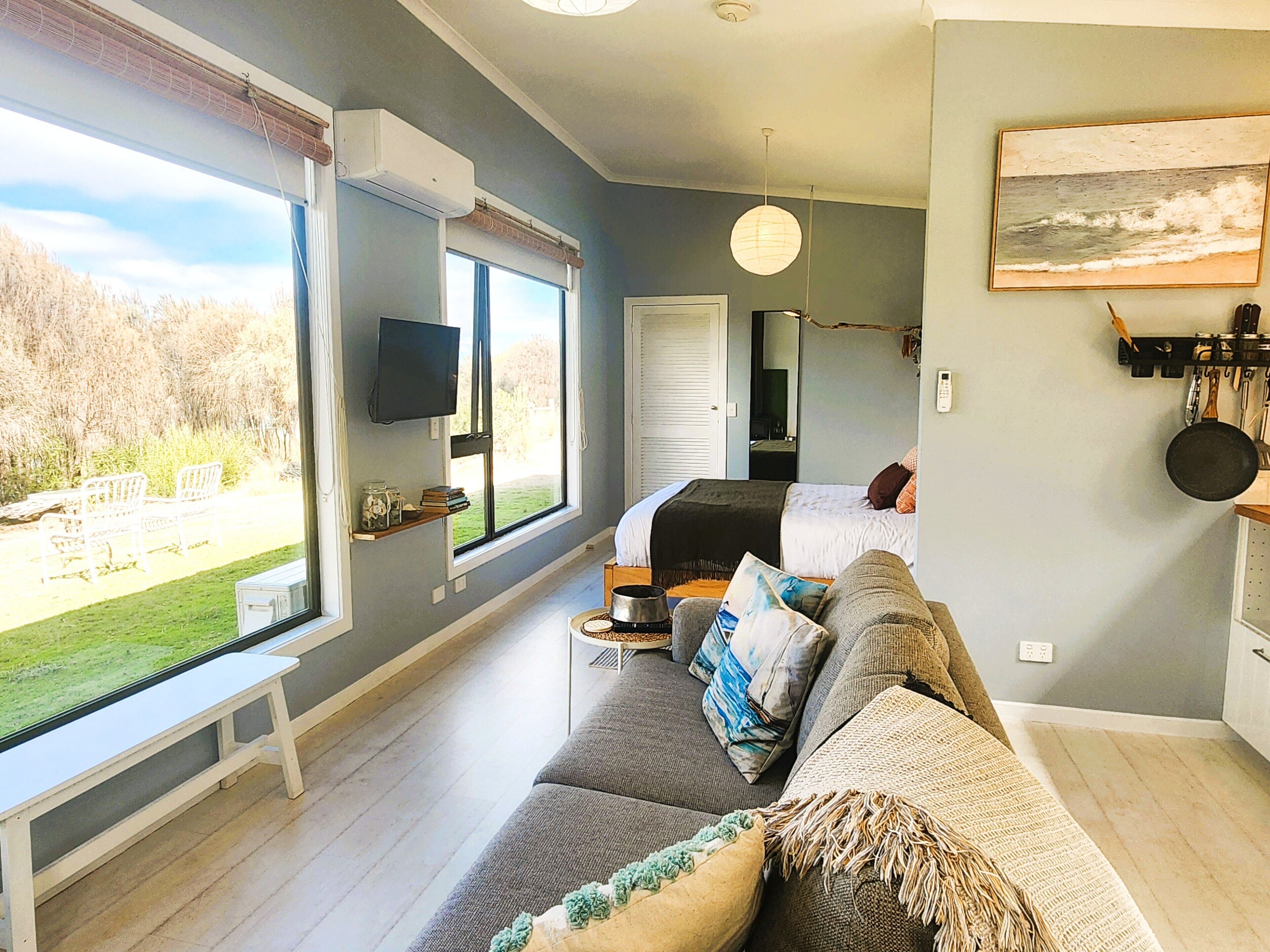 A modern bedroom with a large window, a flat-screen TV, and a bed with a headboard.
