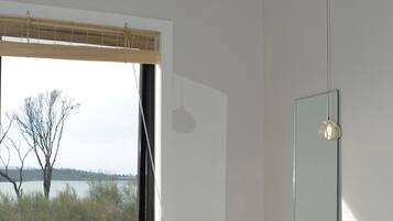 A bathroom with a large window, a white sink, and a mirror.