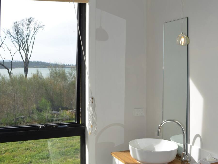 A bathroom with a large window, a white sink, and a mirror.