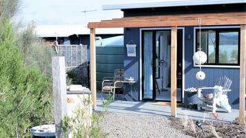 Ein modernes Haus mit einer überdachten Terrasse, einer Holzterrasse und einer Schotterauffahrt.