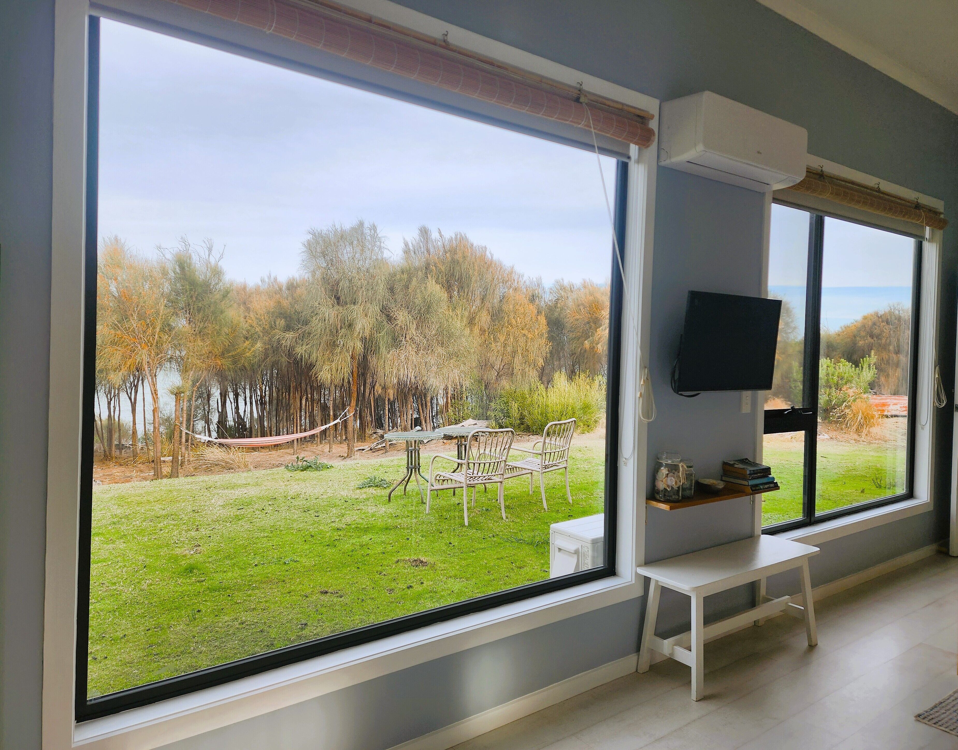 A room with large windows, a TV, and a small table.