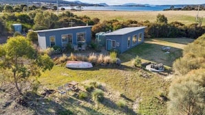 A modern two-story house with a large deck and a view of a lake. - Flotsam Studio Accommodation (Dunalley)