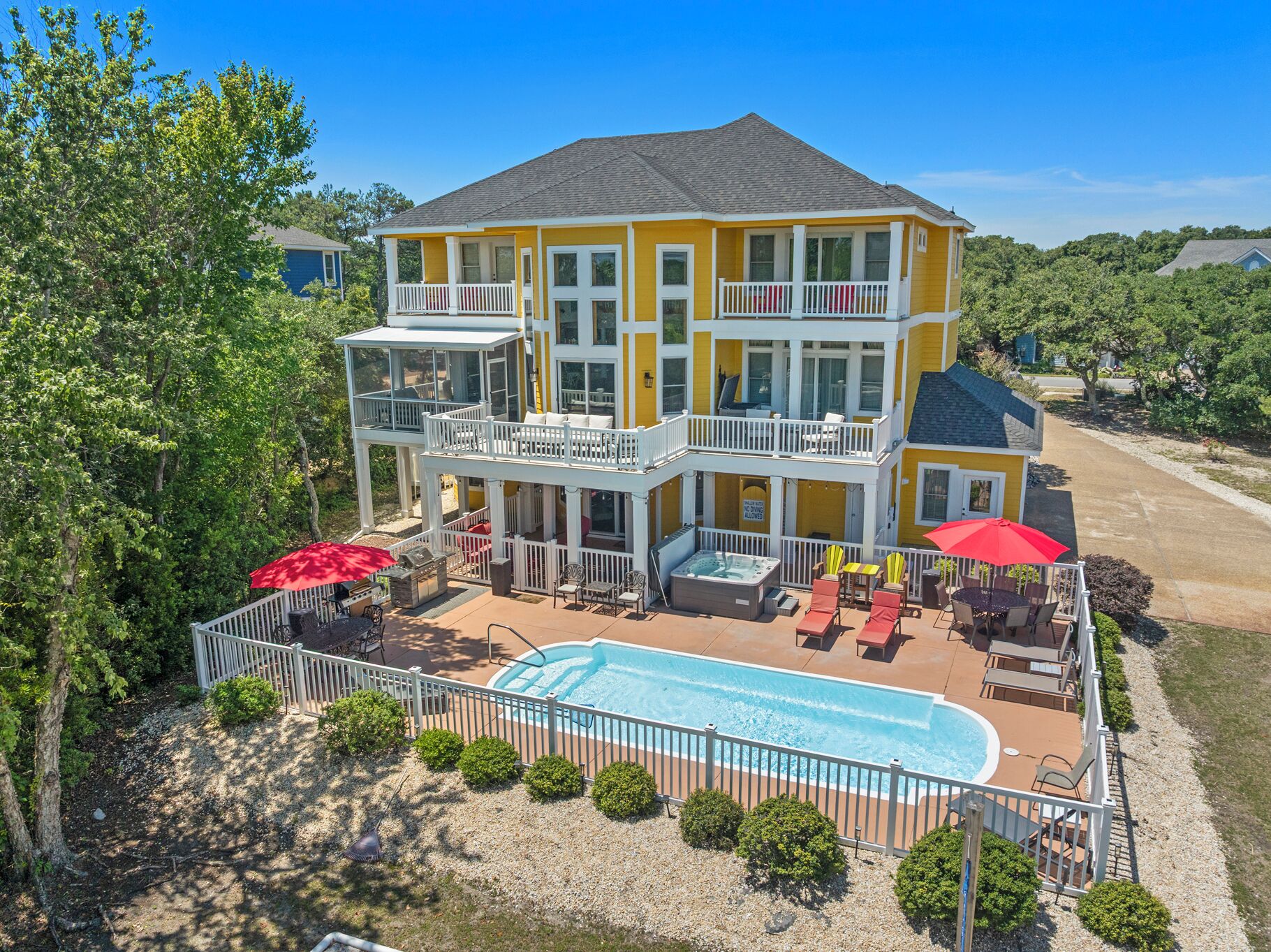 A two-story building with a swimming pool, outdoor seating, and a hot tub.