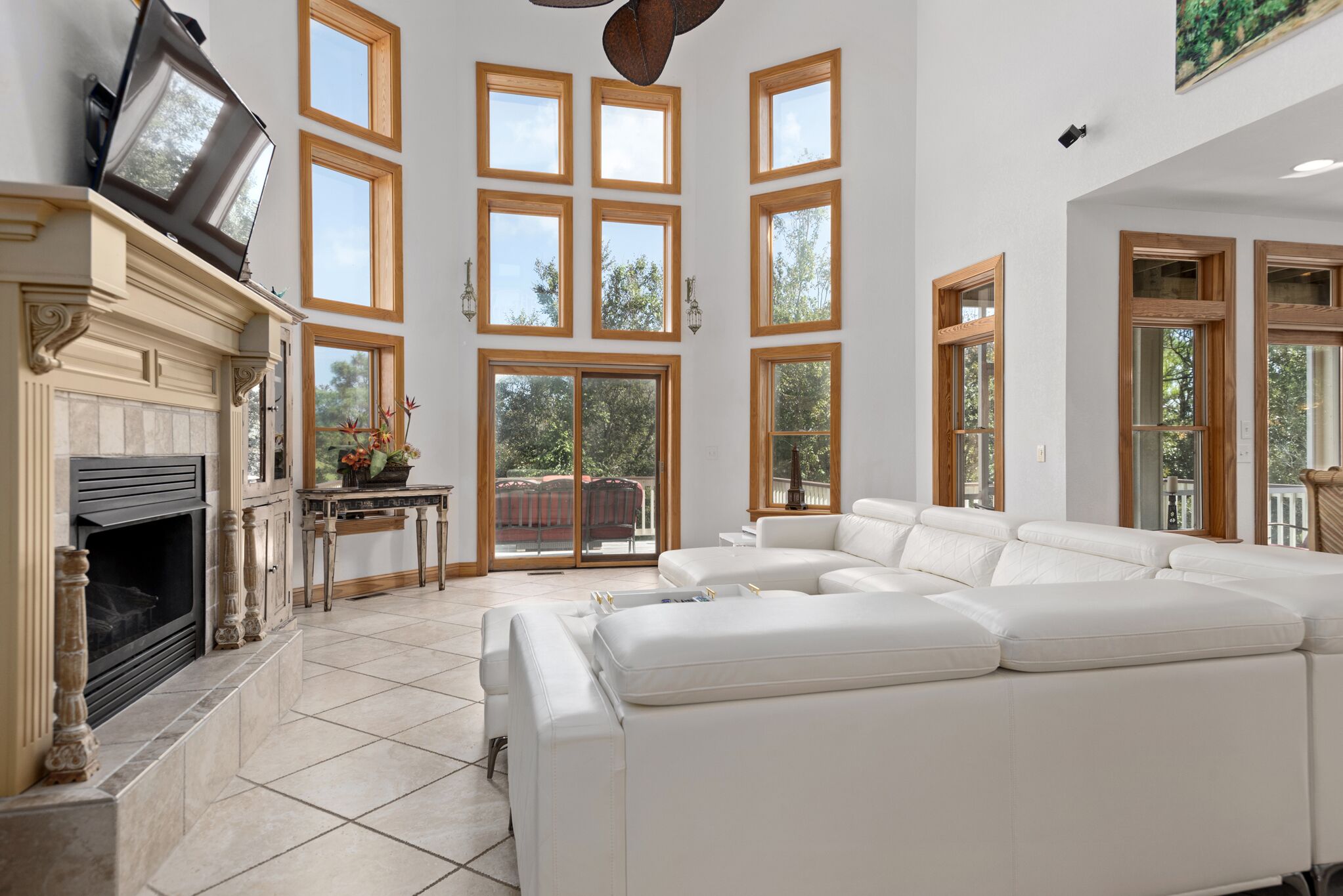 A spacious living room with a fireplace, large windows, and a white leather sofa.