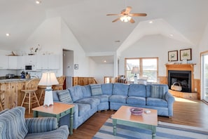 A spacious living area with a large blue sectional sofa, wooden flooring, and a fireplace.
