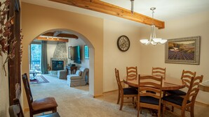 A dining area with wooden chairs and a table, a fireplace, and a clock on the wall. - Ten Mile Suites 103, Breckenridge (Breckenridge)