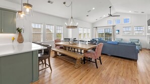 Une cuisine spacieuse avec un coin repas, un ventilateur de plafond et de grandes fenêtres.