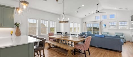A spacious kitchen with a dining area, a ceiling fan, and large windows.