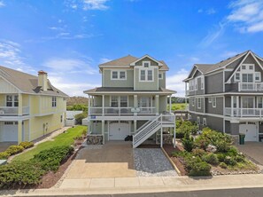 A two-story residential building with a covered front porch and a staircase leading to the upper level.