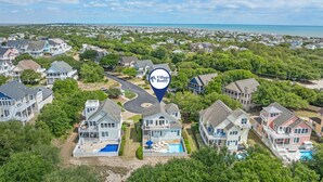 Un quartier résidentiel avec des maisons, une piscine et une plage en arrière-plan.