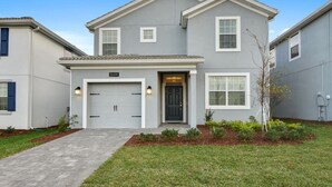 A two-story house with a garage, a front door, and a small garden area.