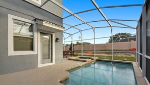 A covered outdoor swimming pool with a patio area, a door, and a window.