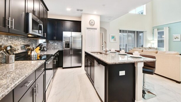 A modern kitchen with dark cabinets, stainless steel appliances, and a central island.