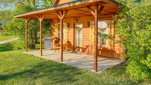 Eine Blockhütte mit Veranda, Grill und Schaukelstuhl.