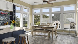 A spacious kitchen with a large island, white cabinetry, and a dining area with a wooden table and chairs. - Y7 Fairways & Sunsets: Pool, Spa, Elevator (Corolla)