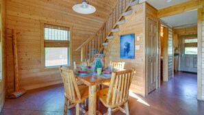 A wooden interior with a dining table set for four, a staircase, and a kitchen area. - Lakefront Vacation Rental w/ Patio & Grill! (Columbia)