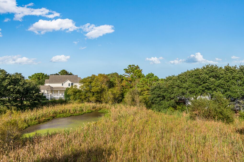 A house surrounded by dense greenery and a small water body.