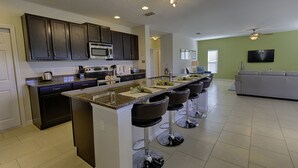 Una cocina moderna con armarios de madera oscura, una isla grande con taburetes de bar, un microondas y una estufa a gas.