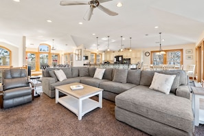 A spacious living room with a large sectional sofa, a leather recliner, and a coffee table.