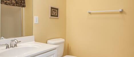 A bathroom with a white sink, toilet, and a towel rack on the wall.