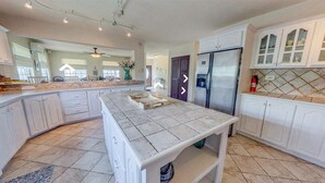 Una cocina amplia con armarios blancos, una isla grande y un refrigerador de acero inoxidable.