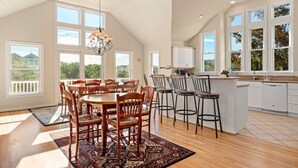 A spacious kitchen with a central island, large windows, and a dining area with wooden chairs. - Mon-Elisa: Private Pool, Hot Tub, Club Access (Corolla)