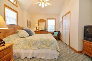Ein Schlafzimmer mit Bett, Kommode, Fernseher und Deckenventilator.