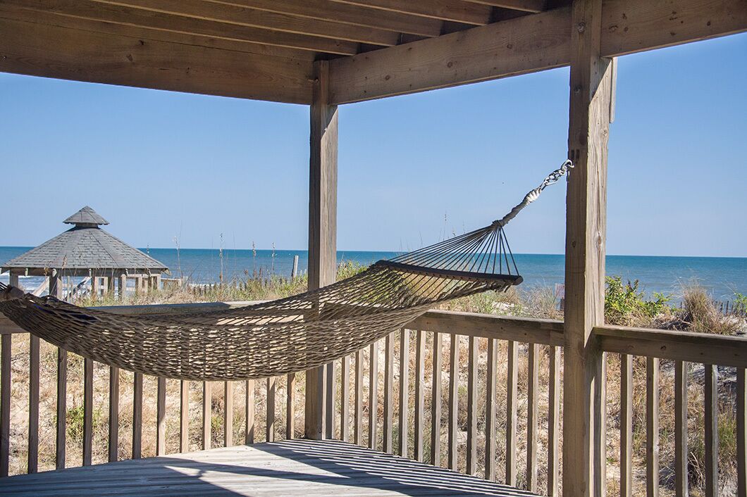 Eine Holzterrasse mit einer Hängematte und einem Pavillon mit Blick auf den Strand.