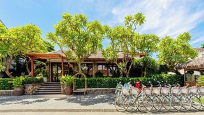 Ein Resort mit überdachter Einfahrt, einer Treppe, die zum Hauptgebäude führt, und einer Reihe Fahrrädern, die draußen abgestellt sind.