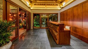 A reception area with a wooden reception desk, a stone wall, and a glass door leading to a garden. - Hoi An Eco Lodge & Spa (Da Nang)