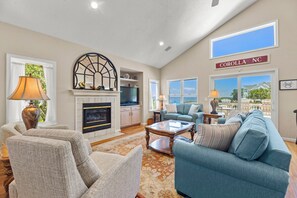 A spacious living room with a fireplace, comfortable seating, and large windows offering a view.