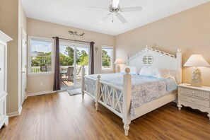 Ein Schlafzimmer mit Bett, Nachttischen, Deckenventilator und Blick ins Freie.