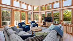 A spacious living room with a large sectional sofa, two armchairs, a coffee table, and a TV. The room features large windows and a balcony. - Always Summer: Private Pool, Spa, Club Access (Corolla)