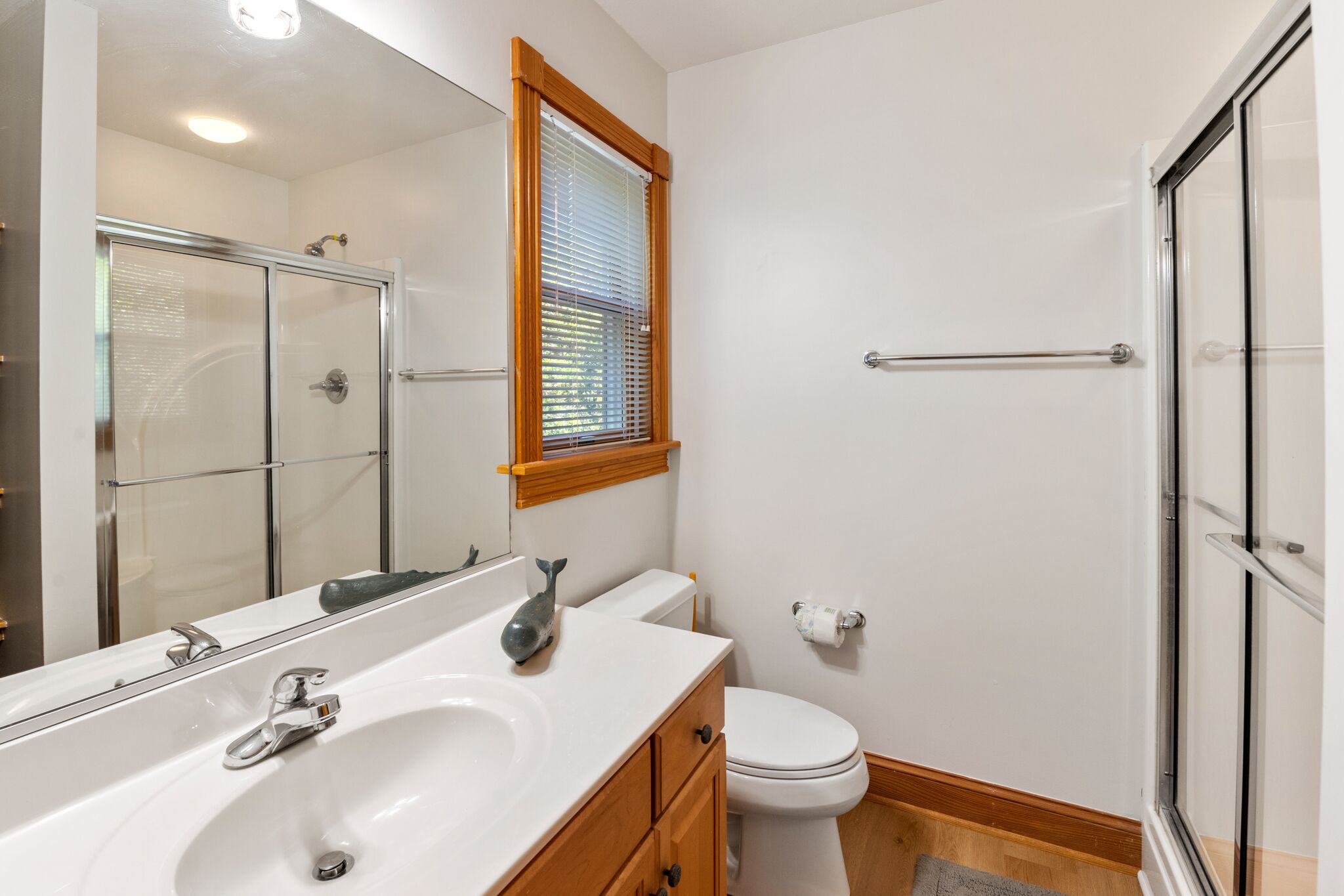 A bathroom with a glass shower enclosure, a white sink with a mirror, and a toilet.
