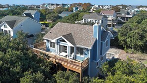 Zona residencial com casas que apresentam uma variedade de estilos arquitetônicos, incluindo uma casa azul imponente com varanda e deck de madeira.