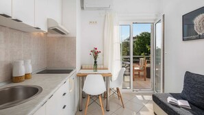 A compact kitchen with a dining area, a sofa, and a view of a park. - Apartment Arausa with Pool II (Vodice)