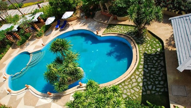 A swimming pool surrounded by palm trees and lounge chairs. - Khaoyai Fahsai Resort (Pak Chong)