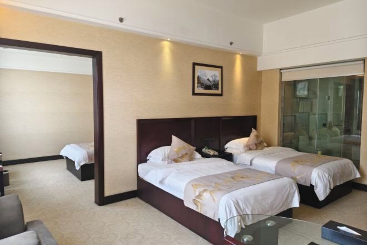 Habitación de hotel con dos camas, un separador de vidrio, un escritorio y una silla.