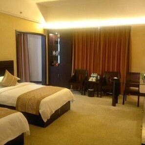 Une chambre d’hôtel avec deux lits, un bureau et une chaise.