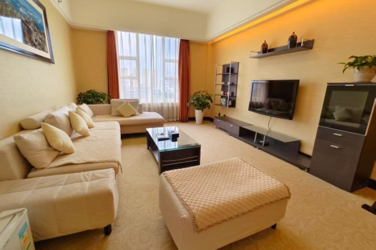 Una sala de estar con sofá, reposapiés, mesa de centro, televisor y estanterías.