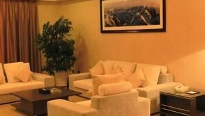 A living room with a sofa set, a coffee table, a side table with a phone, and a framed picture on the wall. - Lide Hotel (Qujing)