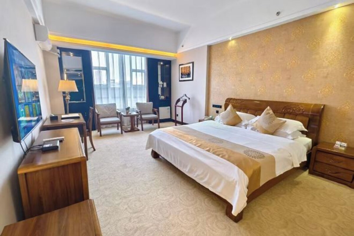 Una habitación de hotel con una cama grande, un escritorio, una silla y un televisor.