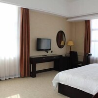 Una habitación de hotel con una cama, un escritorio con televisor, un espejo y una lámpara.