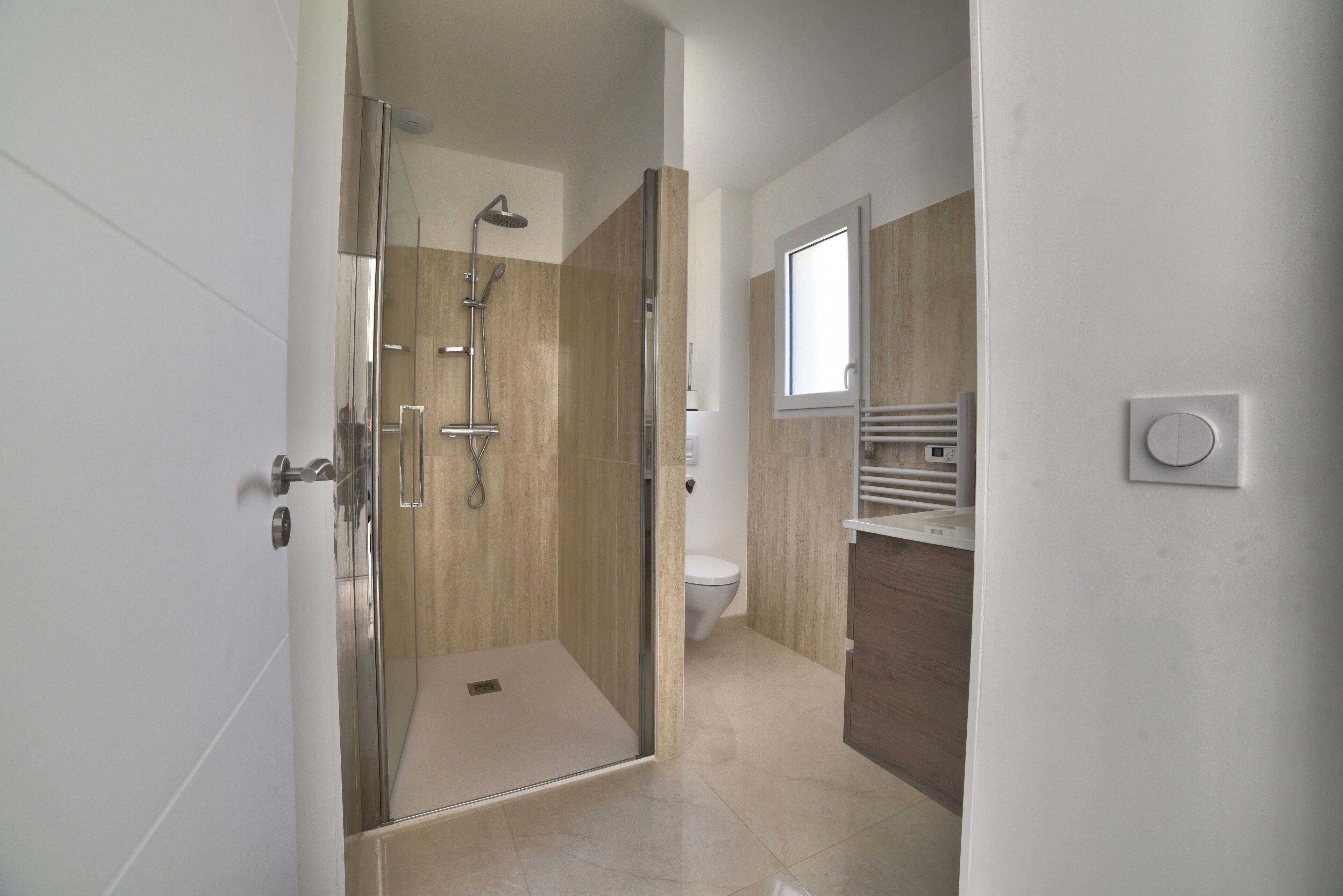Une salle de bain moderne avec une douche à parois de verre, des toilettes et un meuble-lavabo avec un miroir.