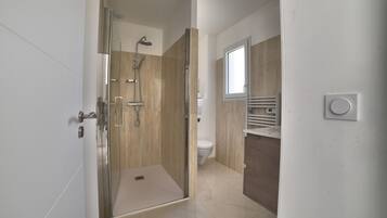 Une salle de bain moderne avec une douche à parois de verre, des toilettes et un meuble-lavabo avec un miroir.