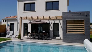 A two-story house with a swimming pool, outdoor seating, and a pergola. - Villa 13 by Avecoeur (Saint-Augustin)