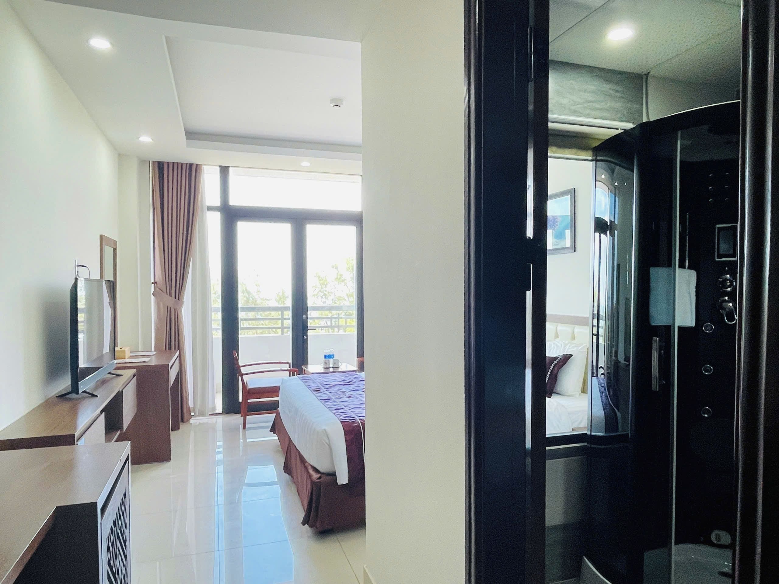 A hotel room with a bed, a desk, a television, and a bathroom with a mirror and sink.